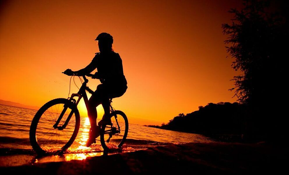 Radfahren am Strand dem Sonnenuntergang entgegen